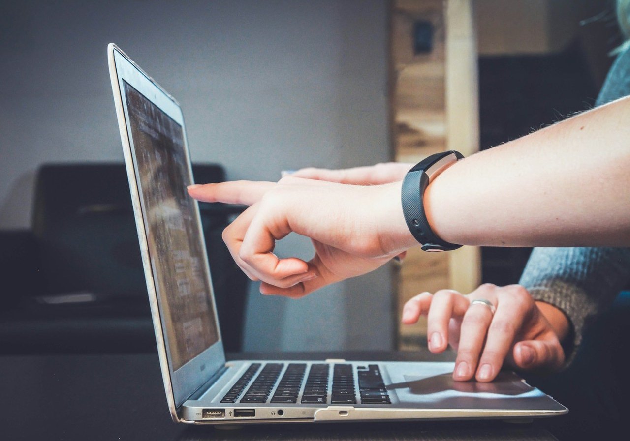 Hands reviewing files on a laptop
